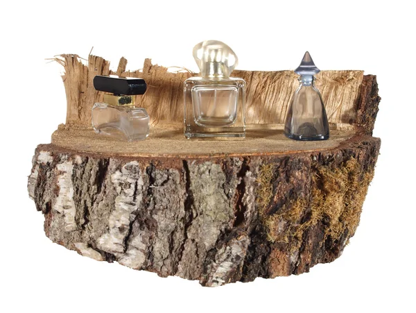 Three empty bottle of perfume on a piece of birch trunk isolated — Stock Photo, Image