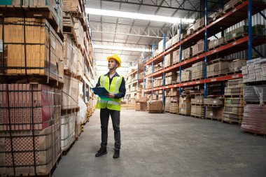 Depo çalışanı büyük bir mağazadaki paketlere bakıyor.