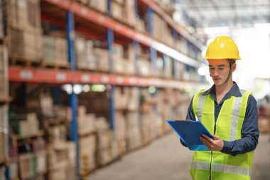 Depo çalışanı büyük bir mağazadaki paketlere bakıyor.