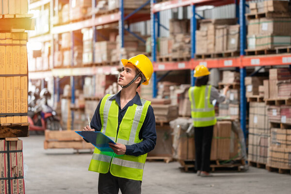 Warehouse worker checking packages on shelf in a large store