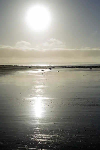 Vara de pesca em uma praia de pôr do sol — Fotografia de Stock