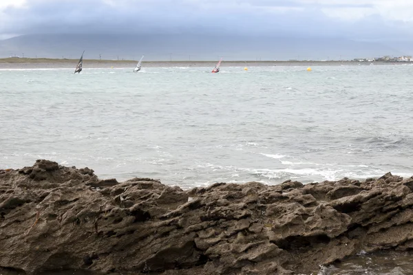 Wind surfers racing in the storm and rocks — Stock Photo, Image