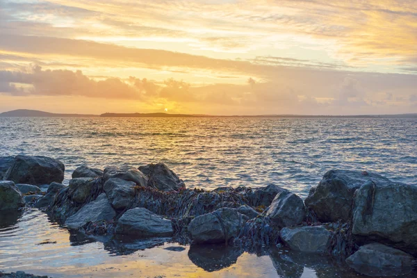 Coucher de soleil jaune et vagues douces à la plage rocheuse beal — Photo