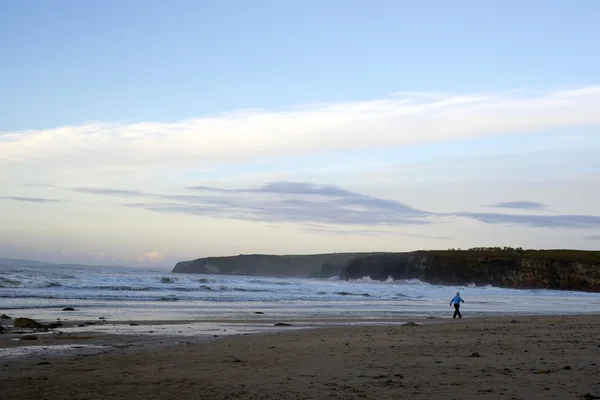 Mujer caminando en la playa fría rocosa — Foto de Stock