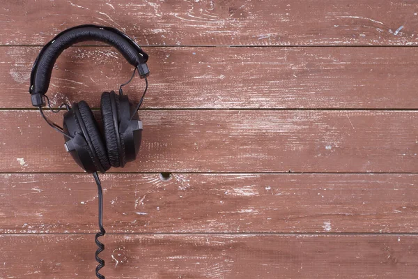 Musical equipment - Black headphone on a wood background.