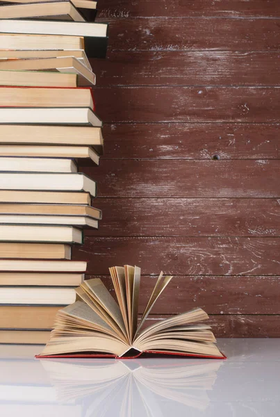 Science and education -  Open book on a group pile books and wooden background. With reflection