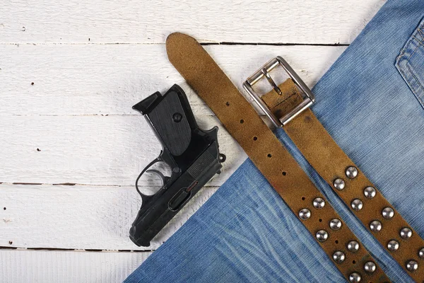 Deski, telefon, zapalniczki, pistolet, niebieskie dżinsy i pasa — Zdjęcie stockowe