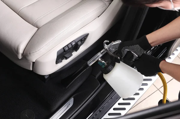 Car service. Worker washing of interior by a special cleaners — Stock Photo, Image