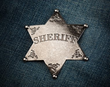 Sheriff star badge on blue denim background clipart