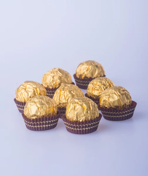 Chocolate ball in a gold foil paper on a background. — Stock Photo, Image