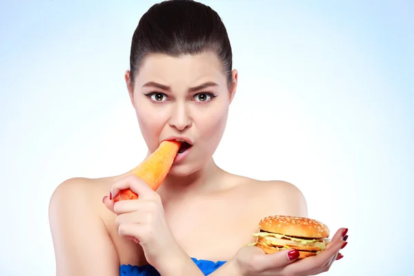 Funny girl eating vegetables on light background — Stock Photo, Image