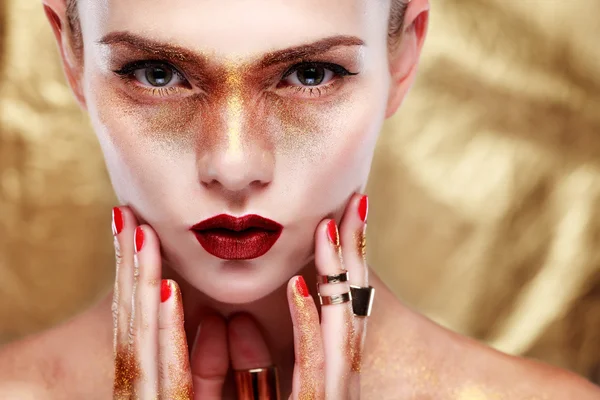 Closeup portrait of sexy  young woman with beautiful blue eyes and red lips on gold  background — Stock Photo, Image