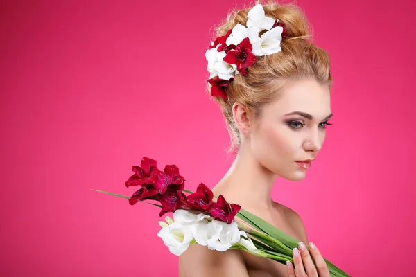 Mooi meisje, geïsoleerd op een roze achtergrond met gekleurde bloemen in haren, emoties, cosmetica — Stockfoto