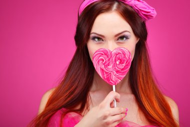 pembe bir arka plan üzerinde büyük bir şeker ile güzel neşeli bir kızıl saçlı kız portresi