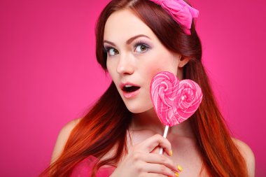 pembe bir arka plan üzerinde büyük bir şeker ile güzel neşeli bir kızıl saçlı kız portresi