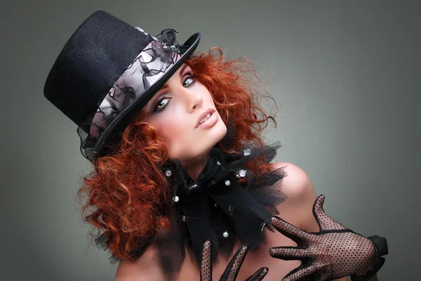 Szép szexuális vörös hajú lány egy fekete kalapot, szürke háttéren portréja. tartozékok. — Stock Fotó