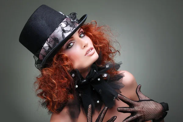 Retrato de una hermosa pelirroja sexual con un sombrero negro sobre un fondo gris. Accesorios . — Foto de Stock