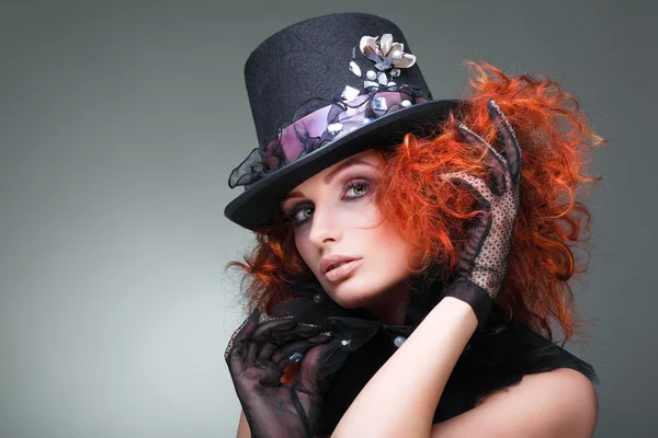 Retrato de una hermosa pelirroja sexual con un sombrero negro sobre un fondo gris. Accesorios . — Foto de Stock