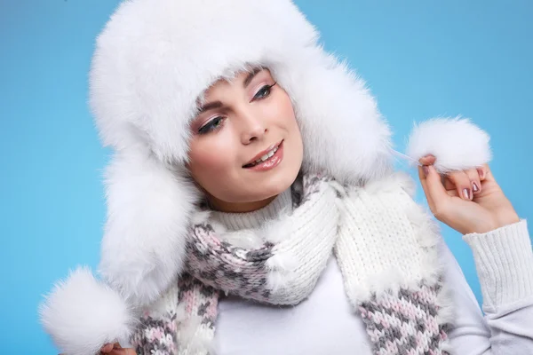 青色の背景に白い毛皮キャップと暖かい服を着て美しい陽気な性的少女 — ストック写真