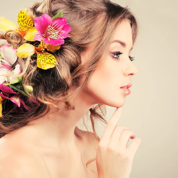 Hermosa chica, aislada sobre un fondo gris claro con flores varicolores en pelos, emociones, cosméticos —  Fotos de Stock