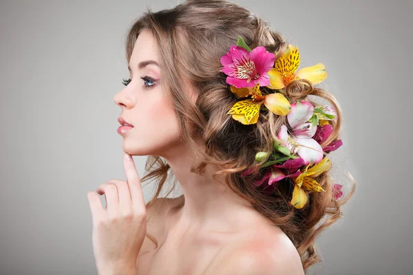 Schönes Mädchen, isoliert auf einem hellgrauen Hintergrund mit bunten Blumen in Haaren, Emotionen, Kosmetik — Stockfoto