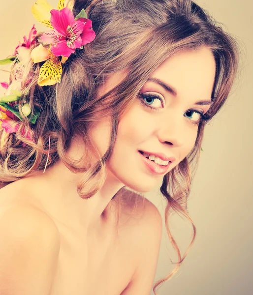 Beautiful  girl, isolated on a light - grey  background with varicoloured flowers  in hairs, emotions, cosmetics — Stock Photo, Image