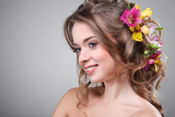 Schönes Mädchen, isoliert auf einem hellgrauen Hintergrund mit bunten Blumen in Haaren, Emotionen, Kosmetik — Stockfoto