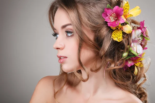 Schönes Mädchen, isoliert auf einem hellgrauen Hintergrund mit bunten Blumen in Haaren, Emotionen, Kosmetik — Stockfoto