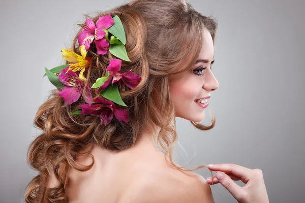 Piękna dziewczyna, na białym tle na światło - szary tło z varicoloured kwiatów w włosy, emocje, kosmetyki — Stockfoto