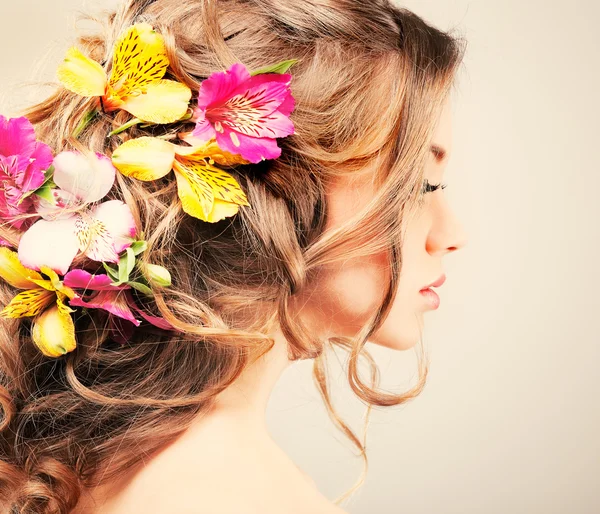 Belle fille, isolée sur un fond gris clair avec des fleurs varicolores en poils, émotions, cosmétiques — Photo