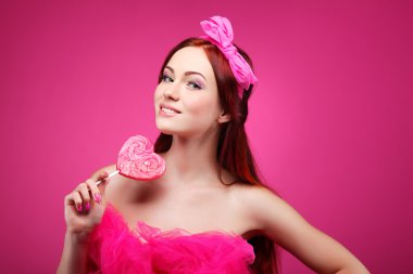 pembe bir arka plan üzerinde büyük bir şeker ile güzel neşeli bir kızıl saçlı kız portresi