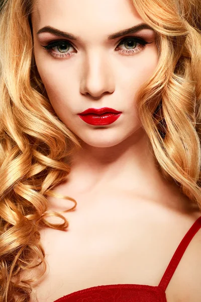 Närbild porträtt av sexig ung kvinna med vackra blå ögon och röda läppar på guld bakgrund — Stockfoto