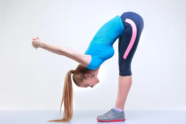 Hermosa joven se dedica a un gimnasio, sobre un fondo gris claro — Foto de Stock