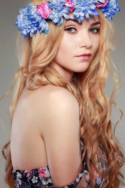 Schönes Mädchen, isoliert auf einem hellgrauen Hintergrund mit bunten Blumen in Haaren, Emotionen, Kosmetik Stockbild