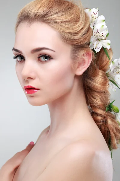 Hermosa chica, aislada sobre un fondo gris claro con flores varicolores en pelos, emociones, cosméticos Fotos de stock libres de derechos