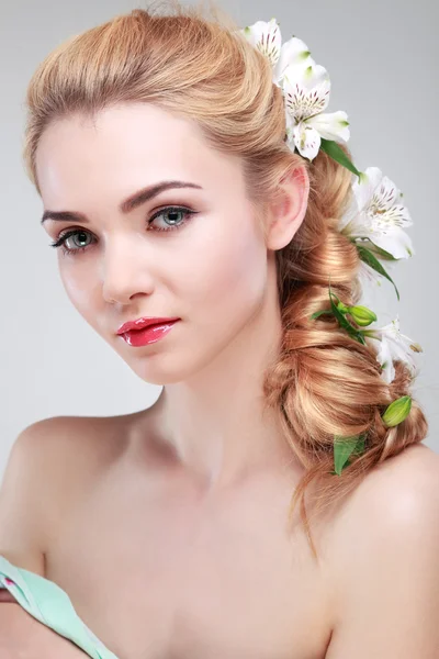 Schönes Mädchen, isoliert auf einem hellgrauen Hintergrund mit bunten Blumen in Haaren, Emotionen, Kosmetik Stockfoto