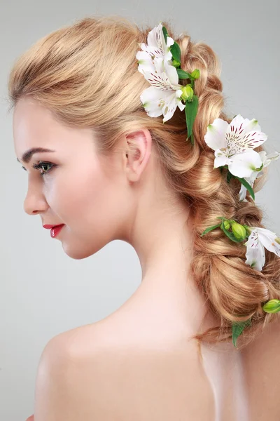 Schönes Mädchen, isoliert auf einem hellgrauen Hintergrund mit bunten Blumen in Haaren, Emotionen, Kosmetik Stockfoto