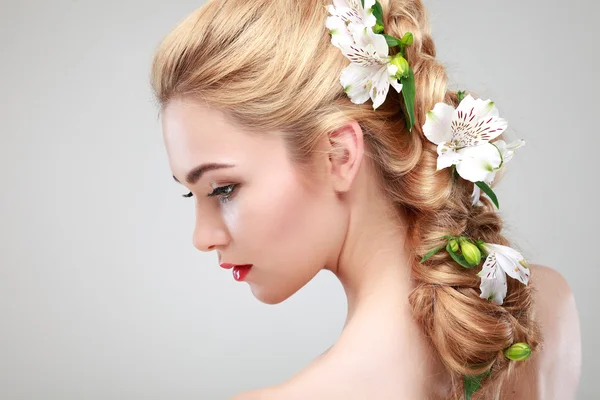 Schönes Mädchen, isoliert auf einem hellgrauen Hintergrund mit bunten Blumen in Haaren, Emotionen, Kosmetik Stockbild