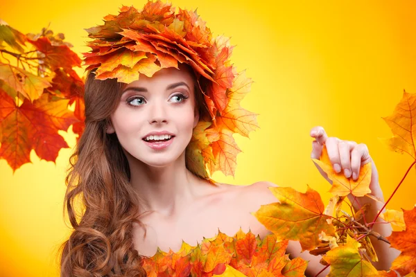 Retrato de cerca de la hermosa joven en una chaplet de hojas de otoño varicolores sobre un fondo amarillo —  Fotos de Stock