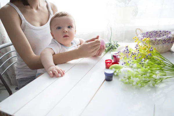 Menino pequeno e sua mãe colorir ovos de Páscoa em casa . — Fotografia de Stock