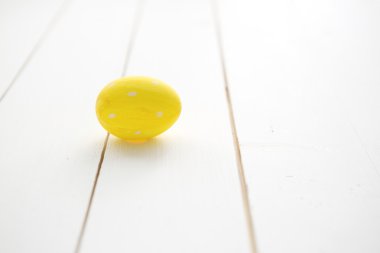 Beyaz ahşap zemin üzerinde bir sarı Paskalya yortusu yumurta