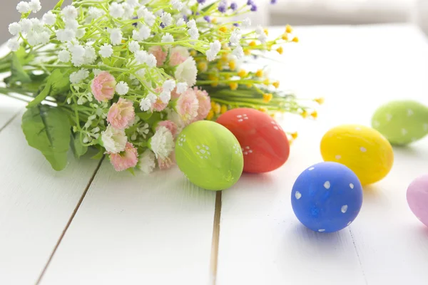 Renkli Paskalya yumurta beyaz ahşap zemin üzerine dekore edilmiştir.. 