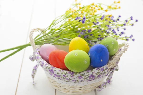Színes Húsvét ikra-ban kosár-fehér fa háttér. — Stock Fotó