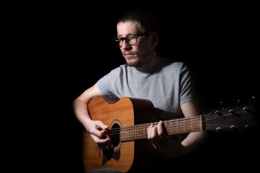 Genç adam akustik gitarla çalıyor. 