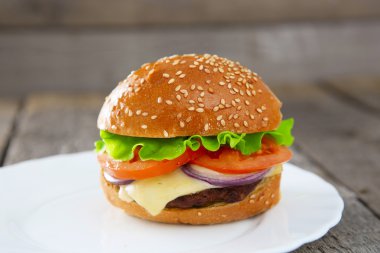Tablo üzerinde beyaz bir tabak içinde Burger