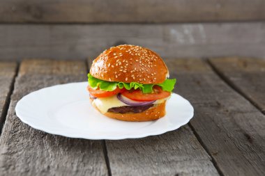 Tablo üzerinde beyaz bir tabak içinde Burger