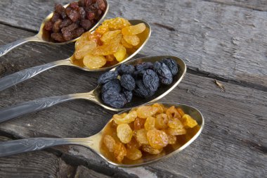 Kuru üzümler ahşap masada metal kaşıklarda