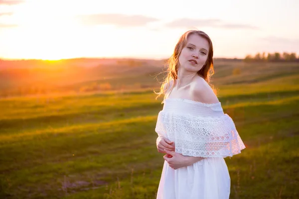 Belle femme souriante dans un champ au coucher du soleil — Photo