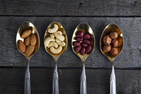 Mixed nuts in metal spoon on wooden table. — Stock Photo, Image