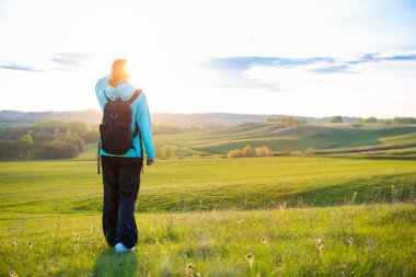 Sırt çantalı genç bir kadın dağda yürüyüş yapıyor.